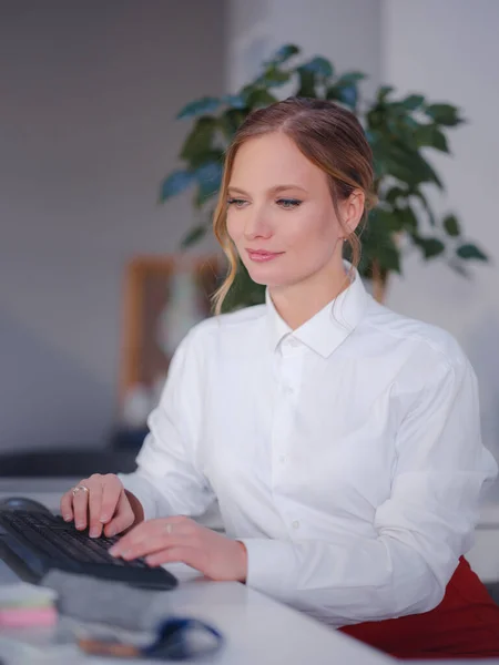 Successful female graphic designer watching textbook about creative ideas on laptop while working process in office. Positive student with blond hair is reading business news on netbook