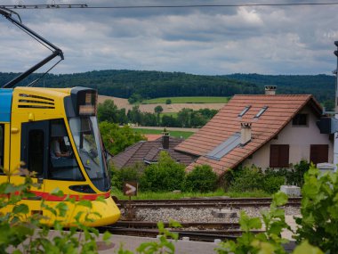 Basel, İsviçre - 7 Temmuz 2022: Şehirde toplu taşıma. Bulutlu bir yaz gününde Basel şehrinde Rodersdorf adlı tramvay istasyonunda sarı BLT tramvayı bekliyor..