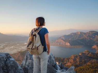 Travel to Turkey, viewpoint over Dalyan Iztuzu Beach. . Smiling woman taking break on hiking trip looking at view at sunset. Explore natural wonders of Turkey
