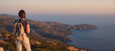 Travel to Turkey, viewpoint over Dalyan Iztuzu Beach. . Smiling woman taking break on hiking trip looking at view at sunset. Explore natural wonders of Turkey