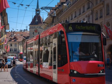 Bern, İsviçre - 6 Temmuz 2022: Şehirde toplu taşıma. İsviçre 'nin başkenti Bern' de güneşli bir yaz gününde yolcuları ve tramvay hattı olan tramvay istasyonu..