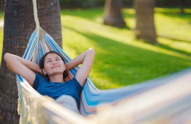 young beautiful lady posing while lying on hammock, beautiful asian woman, brunette resting on vacation, relax, outdoor portrait. long weekend and vacation holidays spent slow life in Turkey