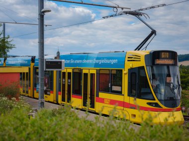 Basel, İsviçre - 7 Temmuz 2022: Şehirde toplu taşıma. Bulutlu bir yaz gününde Basel şehrinde Rodersdorf adlı tramvay istasyonunda sarı BLT tramvayı bekliyor..