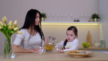 Evde mutfakta kurabiyelerle çay içen bir aile. Anne ve kızı evde birlikte mutlu bir an geçiriyorlar..