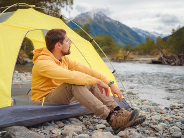 trip to Caucasus mountains, Arkhyz, Teberdinsky reserve. Man traveler relaxing mountains and river in tent camping outdoor Travel adventure lifestyle concept hiking active vacations. wake up in nature