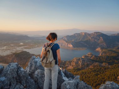 Travel to Turkey, viewpoint over Dalyan Iztuzu Beach. . Smiling woman taking break on hiking trip looking at view at sunset. Explore natural wonders of Turkey