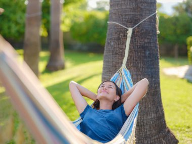young beautiful lady posing while lying on hammock, beautiful asian woman, brunette resting on vacation, relax, outdoor portrait. long weekend and vacation holidays spent slow life in Turkey