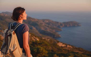 Travel to Turkey, viewpoint over Dalyan Iztuzu Beach. . Smiling woman taking break on hiking trip looking at view at sunset. Explore natural wonders of Turkey