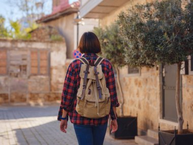 Türkiye 'ye, eski Antalya Kaleci ilçesine, ünlü turizm beldesine gitmek. Mutlu Asyalı bayan turist sırt çantalı gezgin eski şehirde yürüyor..
