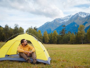 trip to Caucasus mountains, Arkhyz, Teberdinsky reserve. Man traveler relaxing in mountains in tent camping outdoor Travel adventure lifestyle concept hiking active vacations.