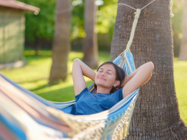 young beautiful lady posing while lying on hammock, beautiful asian woman, brunette resting on vacation, relax, outdoor portrait. long weekend and vacation holidays spent slow life in Turkey