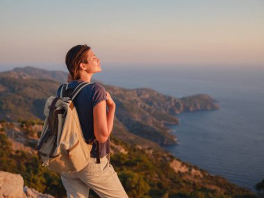 Travel to Turkey, viewpoint over Dalyan Iztuzu Beach. . Smiling woman taking break on hiking trip looking at view at sunset. Explore natural wonders of Turkey