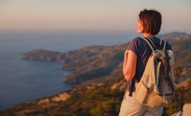 Travel to Turkey, viewpoint over Dalyan Iztuzu Beach. . Smiling woman taking break on hiking trip looking at view at sunset. Explore natural wonders of Turkey