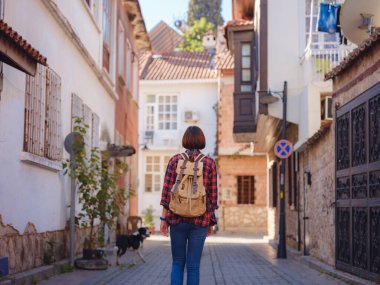 Türkiye 'ye, eski Antalya Kaleci ilçesine, ünlü turizm beldesine gitmek. Mutlu Asyalı bayan turist sırt çantalı gezgin eski şehirde yürüyor..