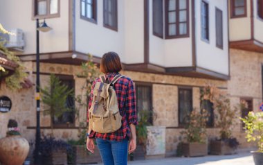 Türkiye 'ye, eski Antalya Kaleci ilçesine, ünlü turizm beldesine gitmek. Mutlu Asyalı bayan turist sırt çantalı gezgin eski şehirde yürüyor..