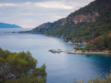 travel to Lagoon in Oludeniz, Fethiye, Turkey. beach near Darbogaz. Winter landscape with mountains, green forest, azure water, beach and cloudy sky