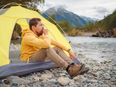 trip to Caucasus mountains, Arkhyz, Teberdinsky reserve. Man traveler relaxing mountains and river in tent camping outdoor Travel adventure lifestyle concept hiking active vacations. wake up in nature