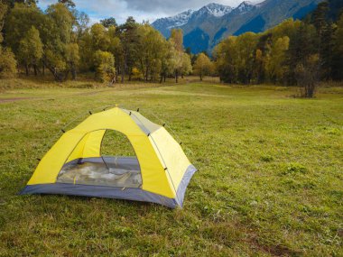 trip to Caucasus mountains, Arkhyz, Teberdinsky reserve. concept of discovery and exploration of wild places in early autumn. yellow tent in autumn valley