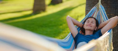 young beautiful lady posing while lying on hammock, beautiful asian woman, brunette resting on vacation, relax, outdoor portrait. long weekend and vacation holidays spent slow life in Turkey