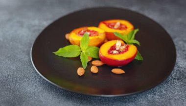 Summer dessert - Cooking Ripe grilled peaches with honey and nuts over dark plate and table. Selective focus with blurred foreground and background. closeup