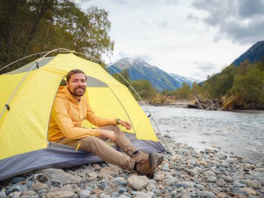trip to Caucasus mountains, Arkhyz, Teberdinsky reserve. Man traveler relaxing mountains and river in tent camping outdoor Travel adventure lifestyle concept hiking active vacations. wake up in nature