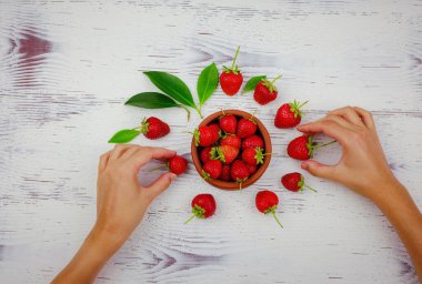 Beyaz arka planda taze organik çilekler. Vejetaryen sağlıklı gıda konsepti. Kadın eli çilek alıyor