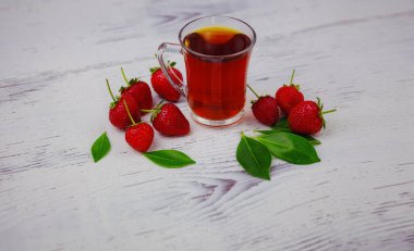 Taze organik çilekler ve cam fincanda siyah çay, beyaz arka planda. Vejetaryen sağlıklı gıda konsepti.