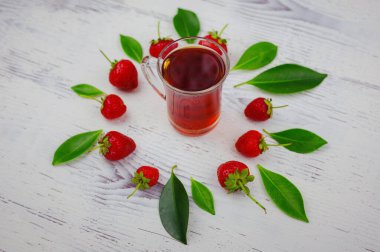 Taze organik çilekler ve cam fincanda siyah çay, beyaz arka planda. Vejetaryen sağlıklı gıda konsepti.