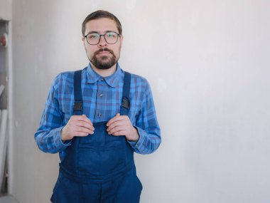 Mavi takım elbiseli genç adam beyaz arka plandaki kameraya bakıyor. Apartman onarımı. Ev yenileme konsepti.