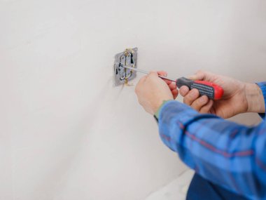 Mavi takım elbiseli genç adam apartman dairesinde çalışıyor. Ev yenileme konsepti. Elektrik soketi kuran elektrikçi