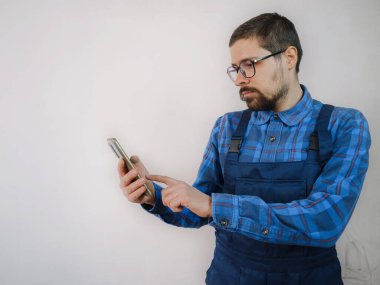 Mavi takım elbiseli genç adam apartman dairesinde çalışıyor. Ev yenileme konsepti. Akıllı telefonlu bir adam cep telefonundan mesaj atıyor ve dinliyor. İnternette çözüm arıyor. Onarım için mal sipariş ediyor.