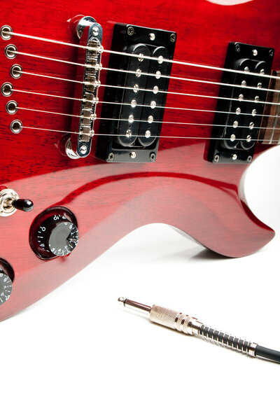 Detail of a wine red color electric guitar with cord.