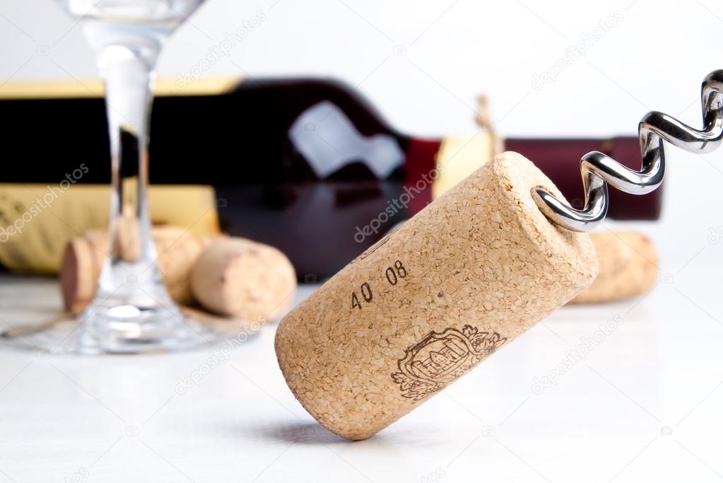 Bottle of wine with corkscrew isolated on white