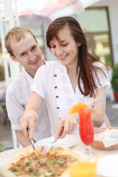 Young couple cutting pizza in cafe — Stock Photo, Image