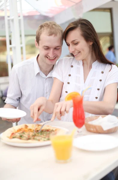 Young couple cutting pizza in cafe — Stock Photo, Image