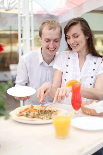 Ungt par skära pizza i café — Stockfoto