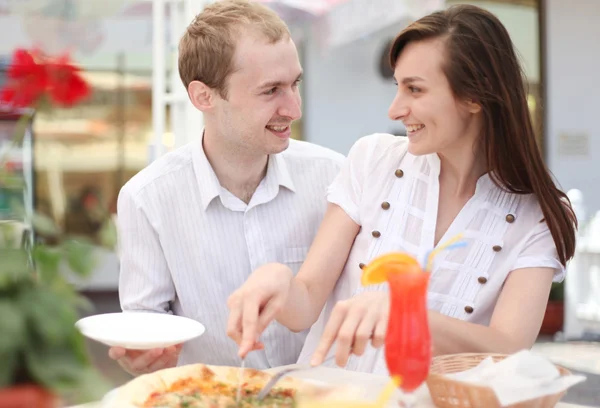 Casal jovem cortando pizza no café — Fotografia de Stock