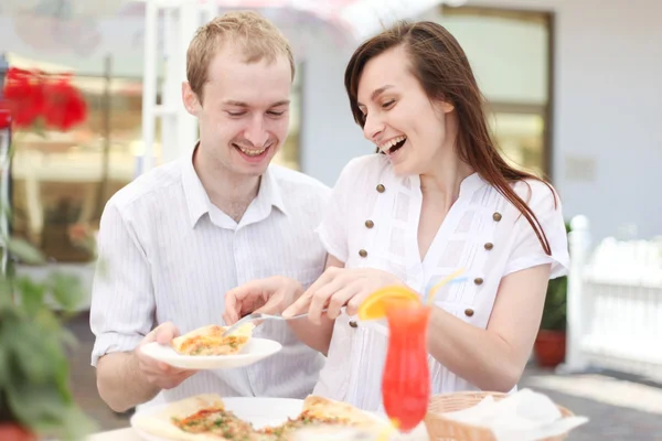 Pareja joven comiendo pizza en la cafetería —  Fotos de Stock