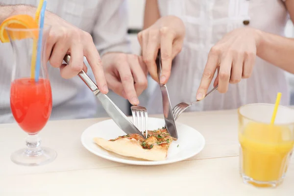 Young couple cutting a slice of pizza in cafe — Stock Photo, Image