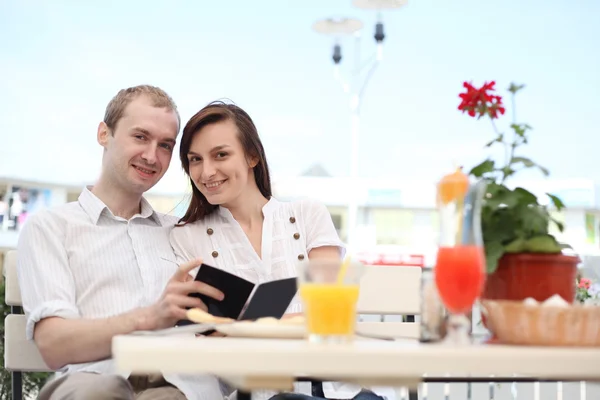 Casal jovem olhando para o menu em um pequeno café — Fotografia de Stock