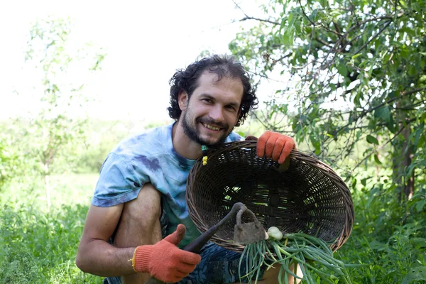 Homem segurando enxada e cebolas verdes — Fotografia de Stock