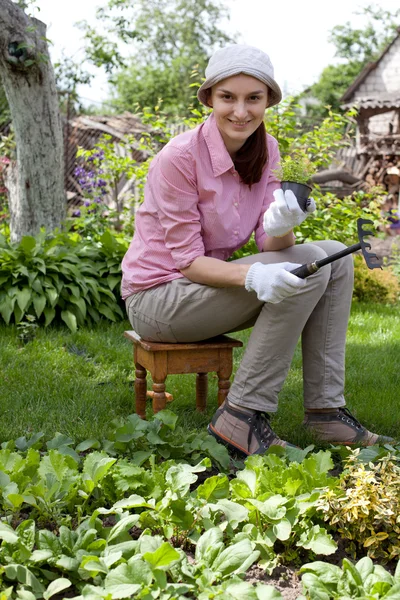 Jonge vrouw met schoffel werken in de tuin bed — Stockfoto