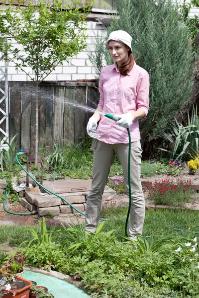 Jonge vrouw drenken de tuin bed — Stockfoto