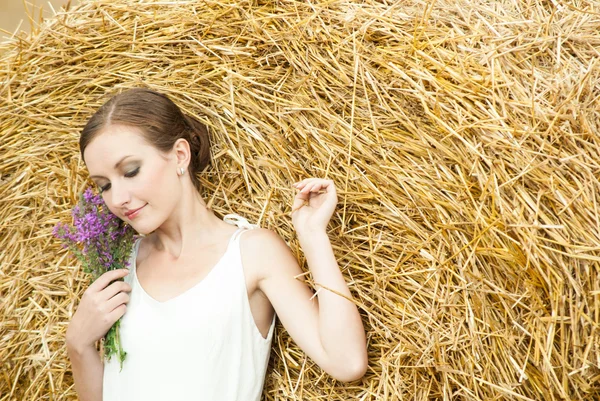 Frau auf einem Heu auf einem Feld außerhalb der Stadt — Stockfoto