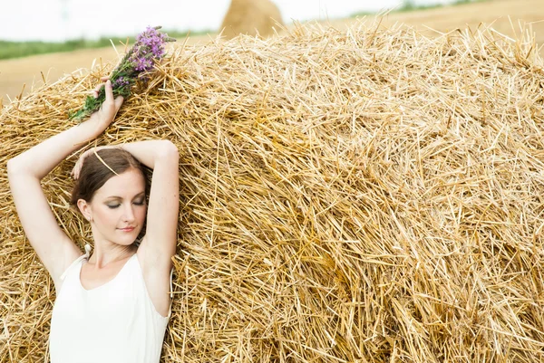 Frau auf einem Heu auf einem Feld außerhalb der Stadt — Stockfoto