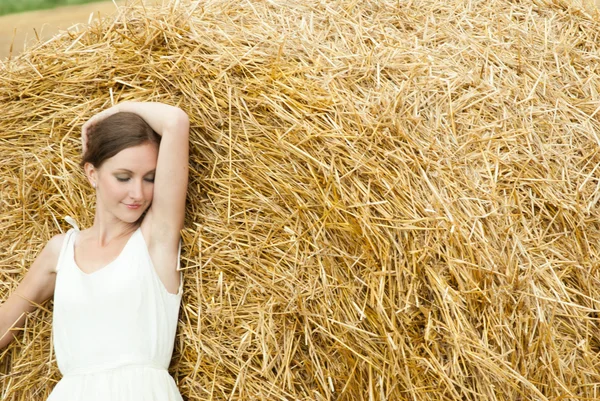 Frau auf einem Heu auf einem Feld außerhalb der Stadt — Stockfoto