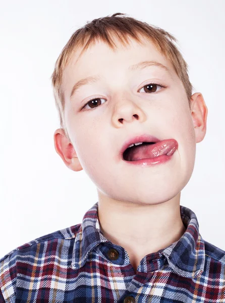 Lite stygg pojke stående sticker ut tungan — Stock fotografie
