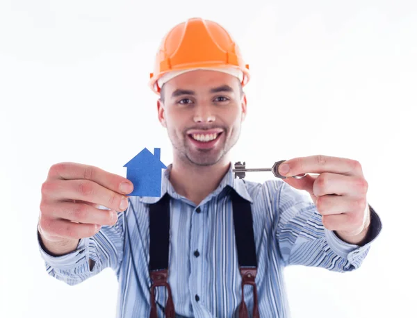 Een man van de bouwer holding een sleutel en een papier-huis. — Stockfoto