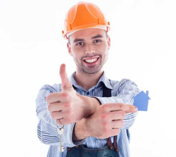 Een man van de bouwer holding een sleutel en een papier-huis. — Stockfoto