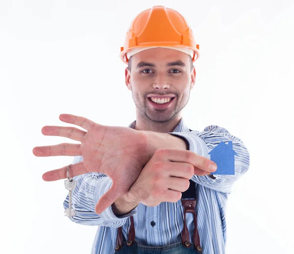 Een man van de bouwer holding een sleutel en een papier-huis. — Stockfoto